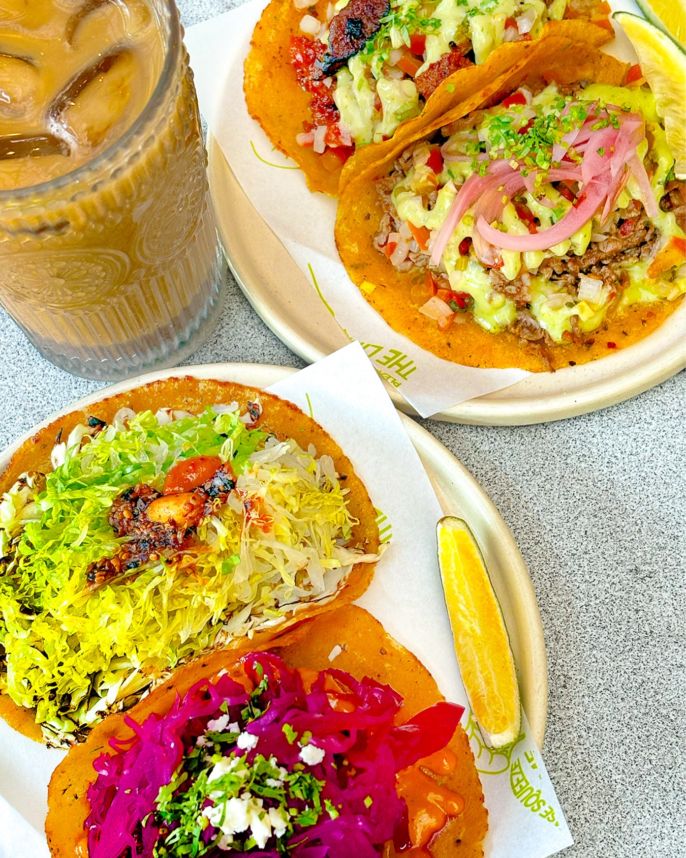 Tequero Tacos assortment — multiple tacos on plates with iced coffee
